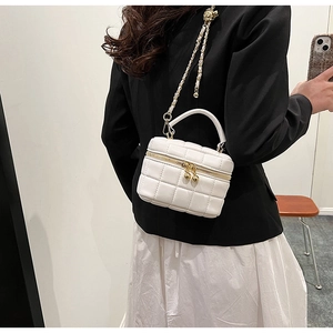 Detail of white quilted leather bucket bag with gold chain strap and dual ball zippers
