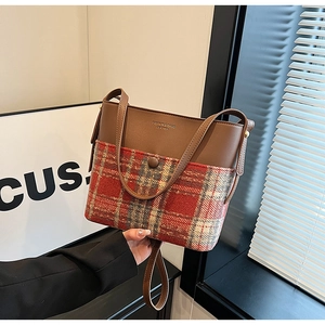 Close-up of retro bucket bag featuring brown leather and plaid fabric texture detail