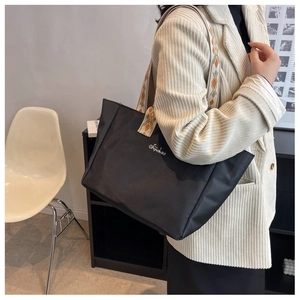Dettaglio della borsa tote nera in nylon con ampia tracolla a motivi geometrici colorati