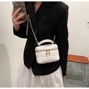 Close-up of a white quilted leather vanity bag with gold chain strap and metal ball zippers