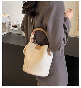 Detail of white lychee leather bucket bag featuring a silk scarf on the handle