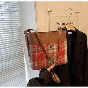 Detail of plaid bucket bag featuring leather patchwork and adjustable shoulder strap