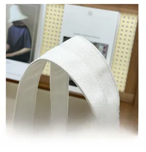 Gros plan des poignées en coton épais et double couture d'un sac cabas en toile blanche