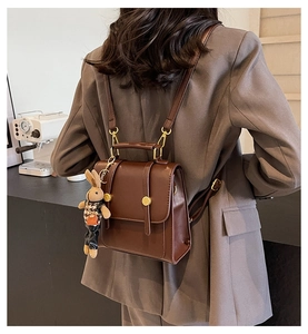 Detail of vintage dark brown leather backpack with bunny pendant worn by a model