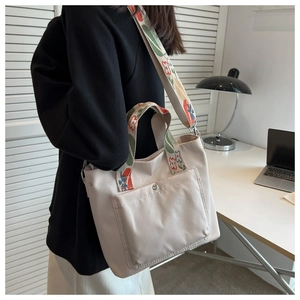 Detail of cream nylon tote bag featuring floral pattern woven handles and a wide shoulder strap