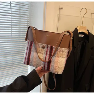 Detail of contrast stitch bucket bag with brown leather and plaid woolen fabric