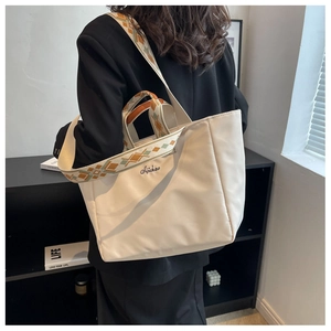Dettaglio della borsa tote in nylon beige con tracolla intrecciata e ricamo decorativo