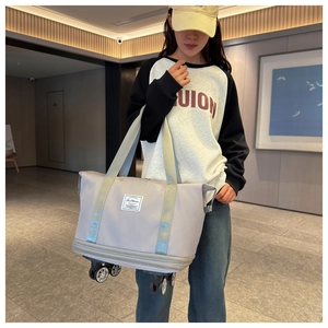 Detail of light grey oxford fabric travel bag with wheels and fashion logo label