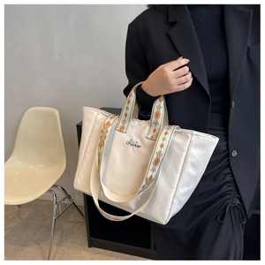 Dettaglio della borsa tote in nylon bianco sporco con tracolle intrecciate etnicre e logo