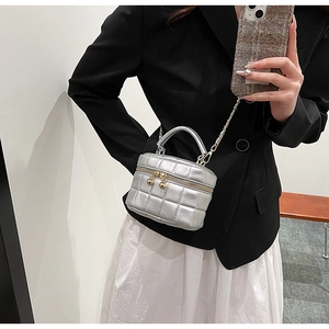 Macro detail of silver quilted mini bucket bag with gold chain and sphere zipper pull