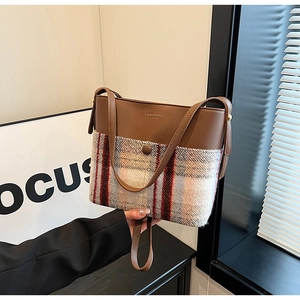 Close-up of brown leather and plaid fabric bucket bag with sleek magnetic closure