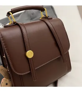 Detail of dark brown vintage faux leather backpack with gold hardware and bear pendant