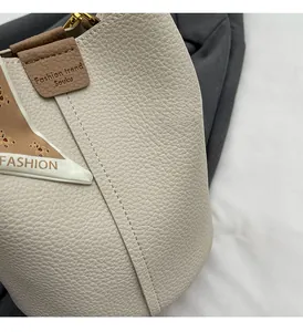 Detailed macro view of litchi grain cream bucket bag with brown trim and silk scarf