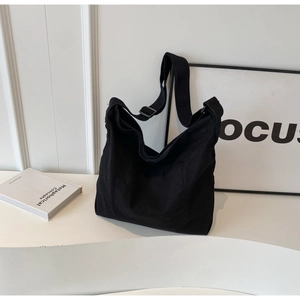 Detail of adjustable shoulder strap and premium black canvas texture on tote bag