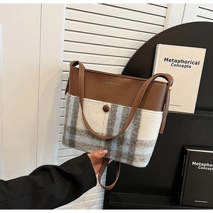 Detail of a chic bucket bag showing mixed brown leather and blue plaid wool textures