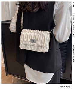 Detail of a quilted crossbody bag with silver twist lock and leather-threaded chain strap