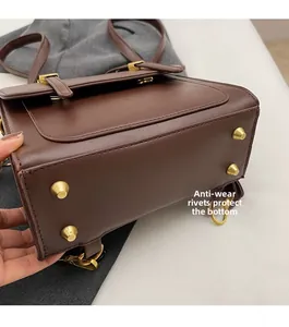 Close-up of golden metal studs on the bottom of a dark brown leather backpack