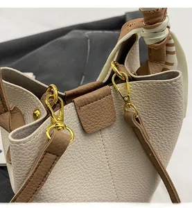 Detail of cross-body bucket bag with beige lychee leather and gold hardware accents