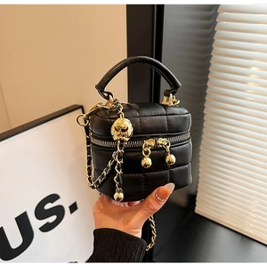 Detail of black quilted leather mini bucket bag with gold chain and round metallic charm