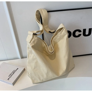 Detailed view of cream canvas tote bag featuring adjustable wide strap and durable texture