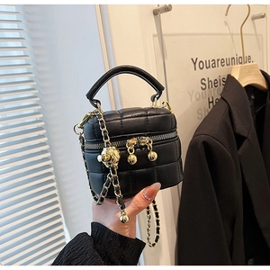 Close-up of black quilted mini bucket bag with gold chain and spherical metal charm