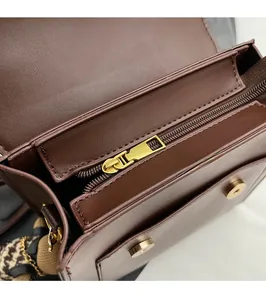 Detailed view of dark brown leather bag with retro gold hardware and magnetic buckles
