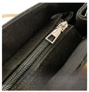 Detail of smooth silver metal zipper on premium black canvas tote bag for commute