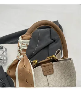 Detail of lychee pattern leather bucket bag with bear print silk scarf on brown handle