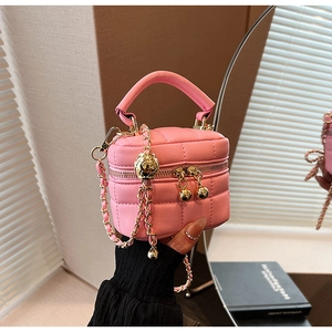 Detailed shot of pink quilted mini bucket bag with gold ball chain and leather top handle