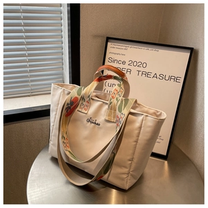Dettaglio macro della borsa tote in nylon beige trapuntato con tracolla floreale