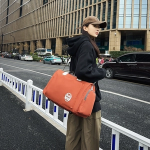 Grand sac de voyage en Oxford orange vif avec écusson 1979 porté par un mannequin