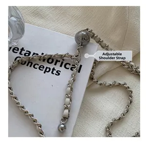 Detail of adjustable metal chain strap with gold-tone sphere slider on white leather bag