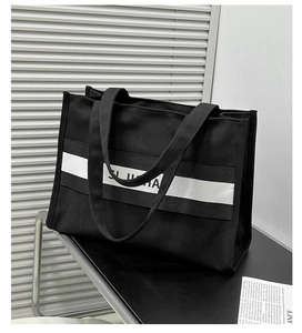 Détail d'un grand sac cabas en toile noire avec de larges rayures blanches et anses tissées