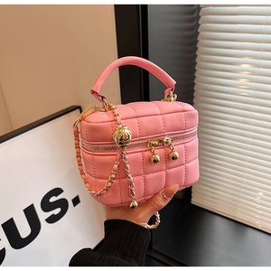 Detailed close-up of pink quilted leather vanity bag with gold chain and ball ornament