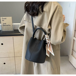 Detail of black lychee grain leather bucket bag with a silk scarf wrapped handle