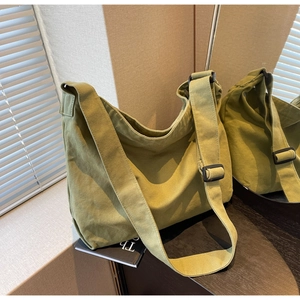 Detailed view of the green canvas crossbody bag featuring an adjustable wide shoulder strap