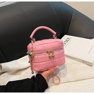Detail of pink quilted bucket bag with golden chain strap and round metal charms