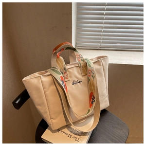 Dettaglio borsa tote beige con ricamo floreale sulla tracolla e logo Sijichao