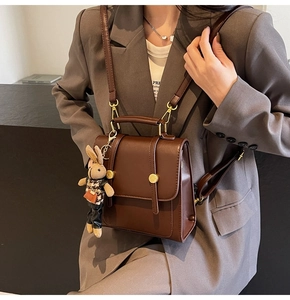 Close-up of vintage brown leather backpack with decorative gold buckles and rabbit charm