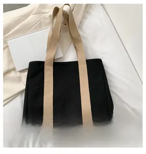 Detail of black canvas tote bag featuring contrast cream straps for school or commuting