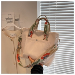 Detail of off-white nylon tote bag with vintage floral patterned handles and strap