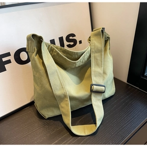Detail of avocado green canvas tote bag showing thick fabric texture and wide shoulder strap