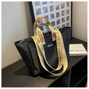 Dettaglio borsa tote in nylon nero con tracolla jacquard geometrica e logo ricamato