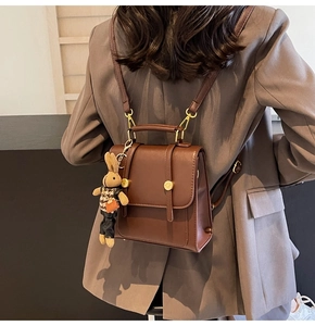 Detail of vintage brown PU leather backpack with gold buckles and a cute rabbit charm