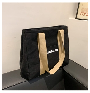Detail of a black and yellow canvas tote bag on a sofa with SIJICHAO lettering