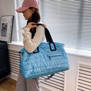 Sac fourre-tout matelassé bleu ciel en nylon avec bandoulières noires porté par un mannequin