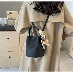 Close-up of black lychee leather bucket bag with decorative silk scarf and handle