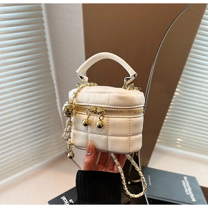 Detail of white quilted bucket bag with gold chain strap and spherical zipper charm