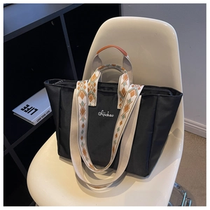 Dettaglio borsa tote in nylon nero con tracolla jacquard e finiture in pelle marrone