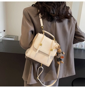 Detail of cream PU backpack with metal buckle and cute bunny plush charm on the side